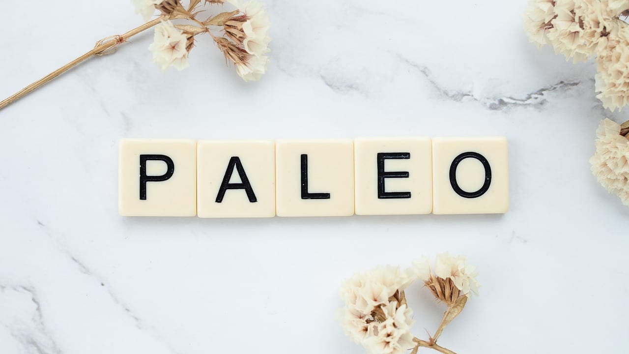 Image showing "PALEO" spelled out with letter tiles on a light surface, surrounded by dried flowers for a minimalist, natural look